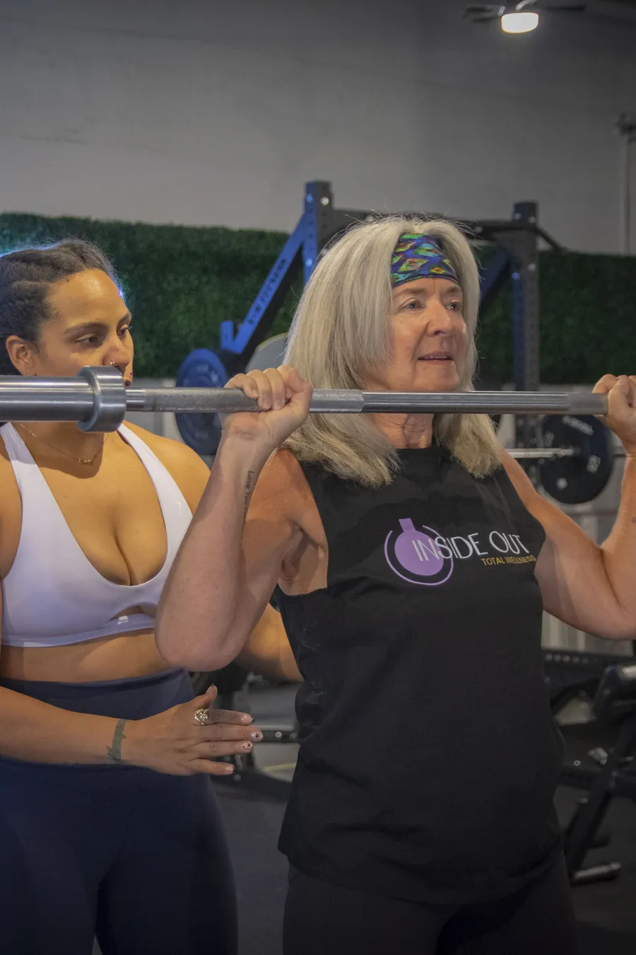 An older adult working with a coach on barbell training at Inside Out Total Wellness in Calgary