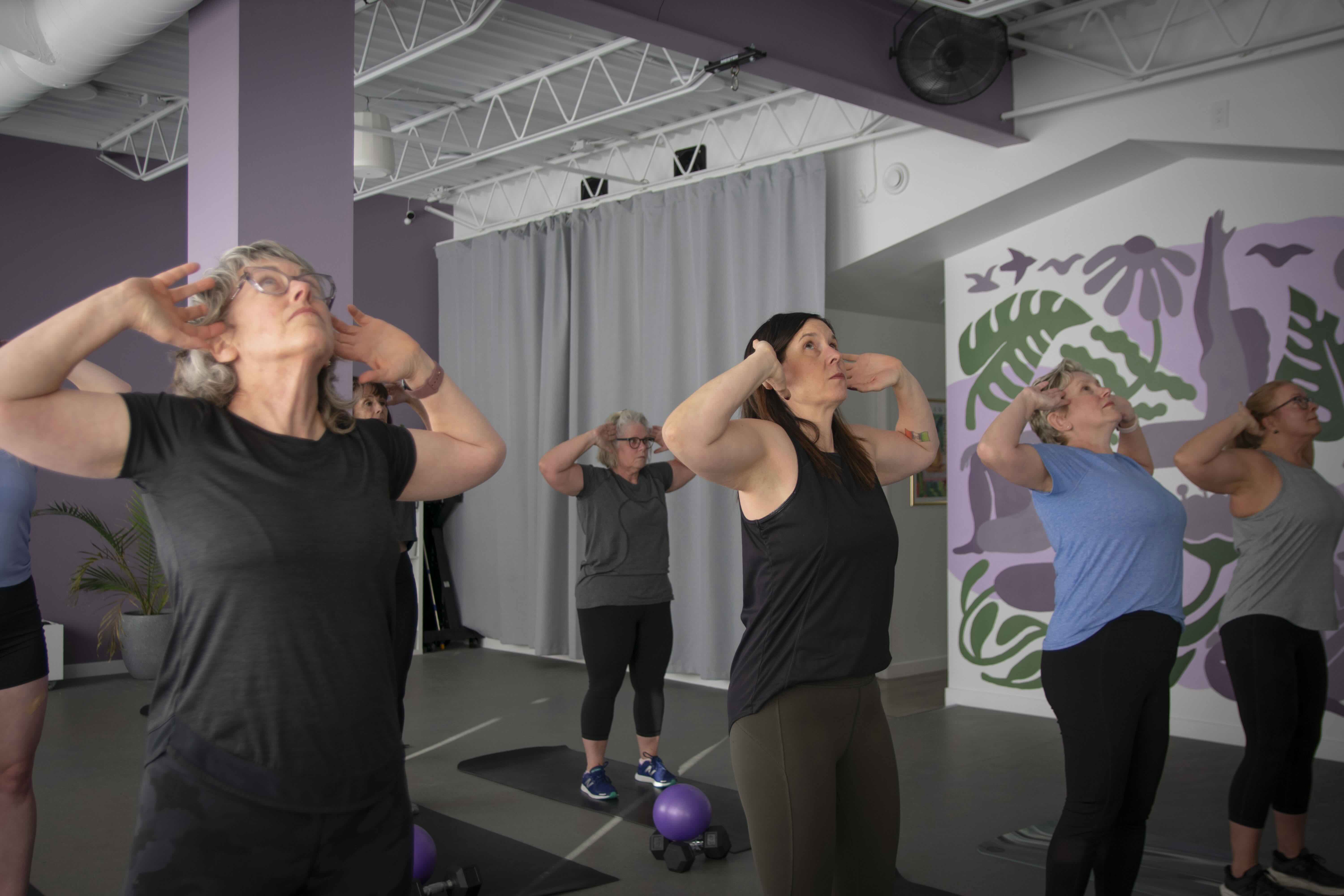 Women lifting dumbbells together, smiling during strength training class